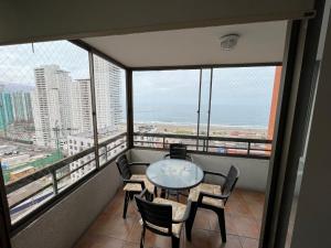 a balcony with a table and chairs in a room with windows at Playa Brava - Iquique in Iquique