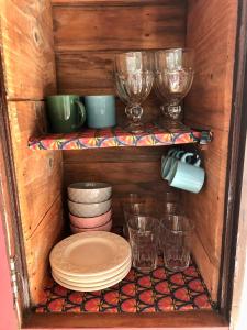 Casa Pintassilgo mini في سانتا كروز كابراليا: خزانة خشبية مع الأطباق والأطباق والأكواب