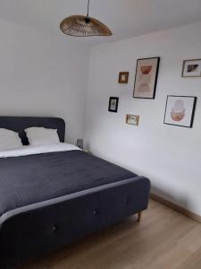 una camera da letto con un letto con una coperta nera e immagini sul muro di T3 avec jacuzzi privé exterieur a Ceyreste