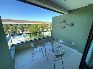 balcón con sillas, mesa y vistas a la piscina en Luxo à Beira-Mar - Flat 2 Quartos no Carneiros Beach Resort, en Praia dos Carneiros