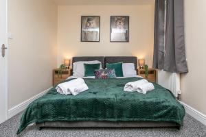 a bedroom with a green bed with two towels at The Durham House in Leyland