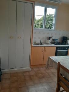 a kitchen with white cabinets and a sink and two windows at Gite des 4 vents in Saint-Mayeux