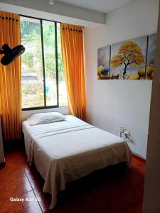 um quarto com uma cama e uma grande janela em Confort Putumayo em Mocoa