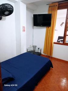 1 dormitorio con 1 cama azul y TV de pantalla plana en Confort Putumayo, en Mocoa