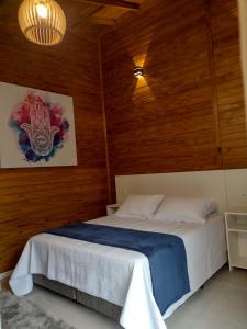 1 dormitorio con 1 cama en una pared de madera en Morada Bem Me Quer, en Canela