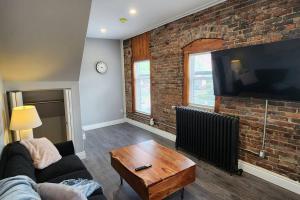 a living room with a couch and a brick wall at Executive 2BD 58inch TV Wifi AC Parking Kitchen in Windsor