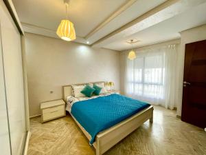 Schlafzimmer mit einem Bett mit blauer Bettwäsche und einem Fenster in der Unterkunft Appartement Tanger Moulay Ismail in Tangier