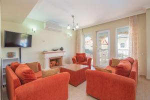 a living room with orange chairs and a fireplace at Golden Trio Villa in Oludeniz