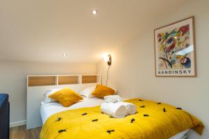 um quarto com uma cama amarela com toalhas em DIFY Soie - Croix-Rousse em Lyon