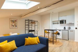 uma sala de estar com um sofá azul e uma cozinha em DIFY Soie - Croix-Rousse em Lyon