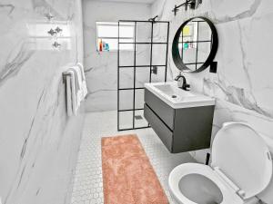 ein weißes Badezimmer mit einem Waschbecken und einem Spiegel in der Unterkunft Tropical 2-Bedroom 1-Bath Private Key West-like Home Close To Beach in Pompano Beach