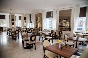 a restaurant with wooden tables and chairs and windows at Hotel Villa Elsa in Bad Kissingen