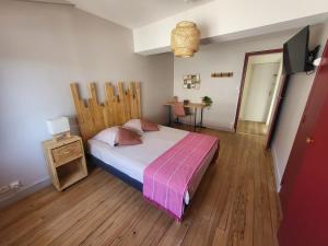 1 dormitorio con 1 cama grande y cabecero de madera en La Maison des Martinettes, en Étauliers