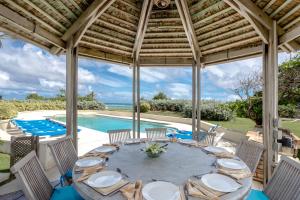 an outdoor dining area with a table and chairs and a pool at Belair Great House - The stunning, private escape with breathtaking views and exquisite surroundings. in Saint Philip