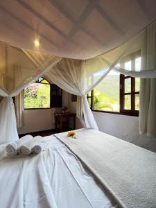 um quarto com uma cama branca e toalhas em Pousada do Capão Chapada Diamantina em Vale do Capao