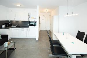 uma cozinha e sala de estar com armários brancos e cadeiras pretas em Ocean Dream 1, FeWo 8 em Duhnen