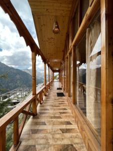 Elle comprend un balcon en bois offrant une vue sur les montagnes. dans l'établissement Odin Hostel Shoja, à Jibhi