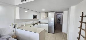 a kitchen with white cabinets and a stainless steel refrigerator at AlmeriaSuite City Centre in Almería