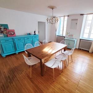 comedor con mesa de madera y sillas blancas en Villa Loha Maison de vacances, en Saint-Gaudens