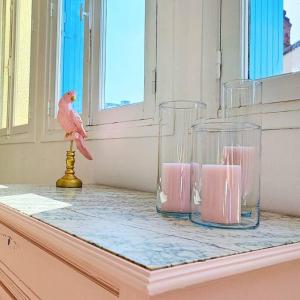 un oiseau rose assis sur un comptoir avec deux vases en verre dans l'établissement Villa Loha Maison de vacances, à Saint-Gaudens