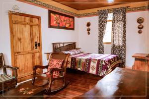 a bedroom with a bed and a chair at Quinta maría isabel. Elegante y restaurada in Gualaceo