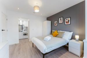 um quarto com uma cama branca e uma parede cinzenta em Perivale Studio Apartments em Perivale