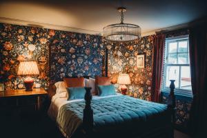 a bedroom with a bed with floral wallpaper and a chandelier at Roslyn House in Tobermory