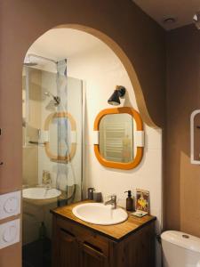 ein Bad mit einem Waschbecken und einem Spiegel in der Unterkunft Cilaos - maisonnette au coeur du medoc in Saint-Laurent-de-Médoc