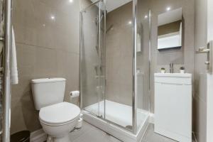 uma casa de banho com um WC e uma cabina de duche em vidro. em Perivale Studio Apartments em Perivale