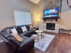 a living room with a leather couch and a fireplace at The Cozy Townhouse WPAFB & WSU in Fairborn