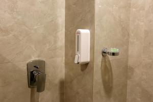 un dispensador de jabón en la pared de una ducha en Hotel Sakura by Maps, en Gurgaon