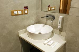uma casa de banho com um lavatório branco e um espelho. em Hotel Sakura by Maps em Gurgaon