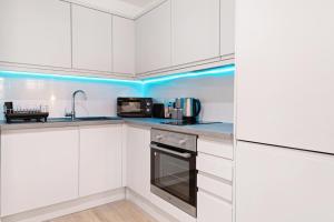 cocina con armarios blancos e iluminación azul en The Market Street Studios en Nottingham