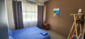 ein Schlafzimmer mit einem blauen Bett und einem Fenster in der Unterkunft Tropical Breeze Apartments in Paramaribo