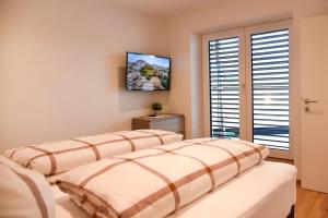 2 letti in una camera da letto con TV a parete di Mountain View Appartements mit Blick NORDKETTENBLICK a Innsbruck