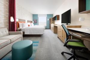 レイクメアリーにあるHome2 Suites By Hilton Lake Mary Orlandoのベッドとデスクが備わるホテルルームです。