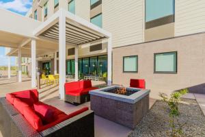 een patio met rode stoelen en een vuurplaats bij Home2 Suites By Hilton Lake Mary Orlando in Lake Mary
