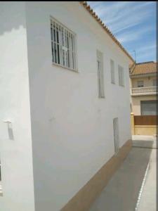 un edificio bianco con due finestre sul lato di Casa en Jerez con patio cerca de la playa y de la sierra a Jerez de la Frontera
