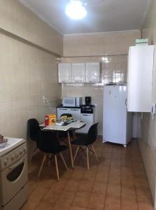 a small kitchen with a table and a white refrigerator at Quarto e sala Boqueirão quadra da praia in Santos
