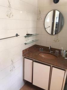 a bathroom with a sink and a mirror at Quarto e sala Boqueirão quadra da praia in Santos