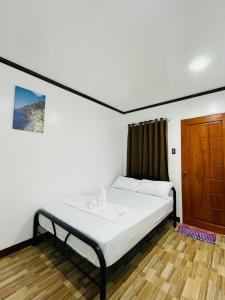 um quarto com uma cama e uma porta de madeira em 3 Sisters Guest House 2 em Moalboal