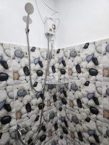 a bathroom with a shower with rocks on the wall at 3 Sisters Guest House 2 in Moalboal