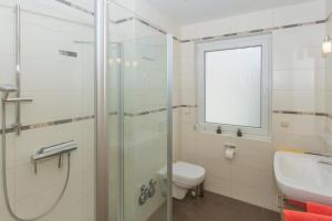 a bathroom with a shower and a toilet and a sink at Wehrbergsdüne 26, FeWo 4 in Duhnen