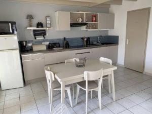 a kitchen with a white table and white chairs at "LA VAGUE" Maison 6 personnes, terrasse, Port plaisance, garage vélos in Talmont