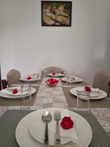 a table with white plates and red roses on it at Keen Leopard Homestay in Jawāi Bāndh +16 photos