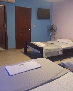 um quarto com 2 camas e uma porta com uma ventoinha em Hotel Los Arcángeles em Cúcuta