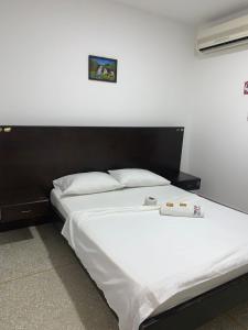 um quarto com uma cama com lençóis brancos e almofadas em Hotel Los Arcángeles em Cúcuta