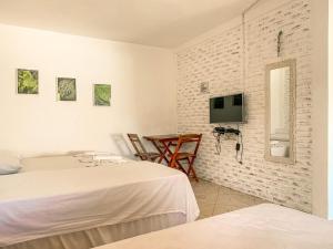 a bedroom with two beds and a tv on the wall at Pousada La Goduria in Canoa Quebrada
