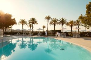 a large swimming pool with chairs and palm trees at Sunwing Alcudia Beach in Alcudia