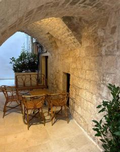 un patio con mesa y sillas en una pared de piedra en Le segrete del Notaio en Conversano